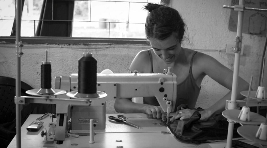 Esta imagen muestra a una persona trabajando con una máquina de coser en un taller.